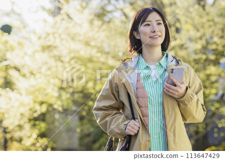 A woman looking at a smartphone outdoors 113647429
