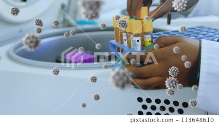 Image of floating macro Covid-19 cells over mixed race doctor checking samples in lab Image of floating macro Covid-19 cells over mixed race doctor checking samples in lab 113648610