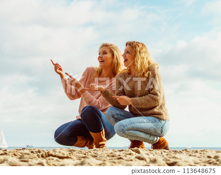 Women on beach having fun pointing Women on beach having fun pointing 113648675