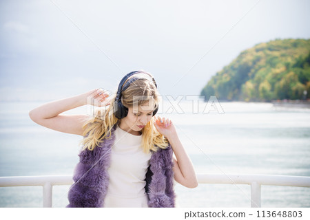 Woman wearing headphones outdoor 113648803
