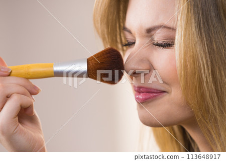Smiling woman holding make up brush 113648917
