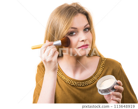 Smiling woman applying face powder Smiling woman applying face powder 113648919