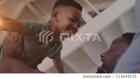 Image of lights over happy african american father and son having fun at home 113649155