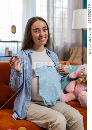 Pregnant woman looking at baby cloth and pacifier, preparing pregnancy, expecting baby, childbirth Pregnant woman looking at baby cloth and pacifier, preparing pregnancy, expecting baby, childbirth 113650039