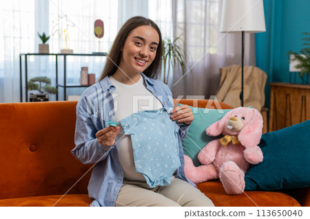 Pregnant woman looking at baby cloth and pacifier, preparing pregnancy, expecting baby, childbirth Pregnant woman looking at baby cloth and pacifier, preparing pregnancy, expecting baby, childbirth 113650040