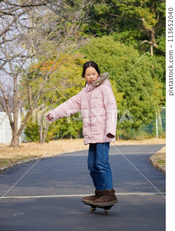 A girl from elementary school playing on a casterboard in a winter park A girl from elementary school playing on a casterboard in a winter park 113652040