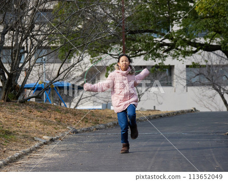 一個小女孩在冬季公園裡高興地玩跳繩 一個小女孩在冬季公園裡高興地玩跳繩 113652049