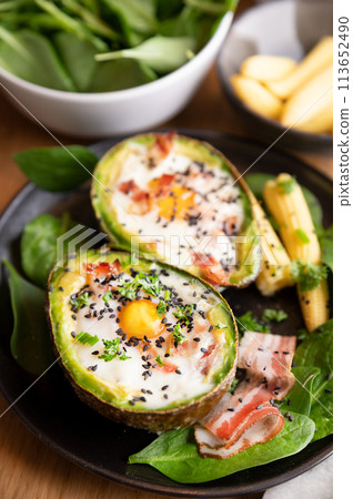Cooking Avocado with Egg and Bacon. The girl prepares a healthy meal, close-up of her hands and Cooking Avocado with Egg and Bacon. The girl prepares a healthy meal, close-up of her hands and 113652490