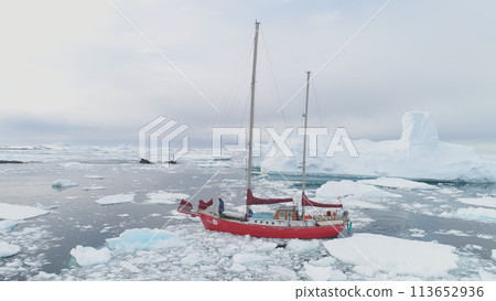 Sailing Yacht Sail in Antarctic Iceberg Ocean Aerial Tracking. Red Vessel Expedition to Polar Nature Glacier Calm Harbour Top Drone 113652936