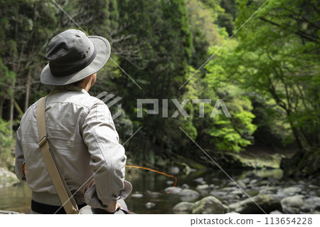 Fisherman standing in a mountain stream Fisherman standing in a mountain stream 113654228