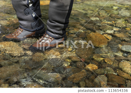The feet of a fisherman walking through the river 113654336