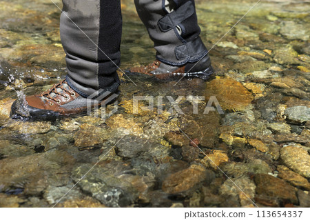 The feet of a fisherman walking through the river 113654337