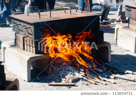 A photo of steaming sweet potatoes over a campfire. The process of cooking sweet potatoes. 113654731