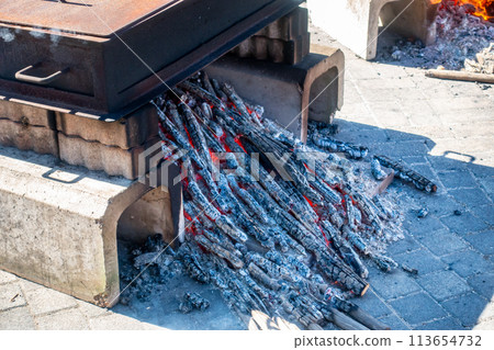 A photo of steaming sweet potatoes over a campfire. The process of cooking sweet potatoes. 113654732