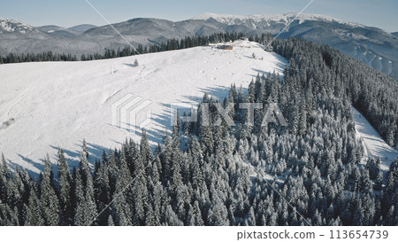 Ski resort at snow mountain top aerial. Nobody nature landscape. Winter snowy slope. Tourists attraction for mountaineering. Vacation for extreme, active sport. Carpathians, Bukovel, Ukraine, Europe 113654739