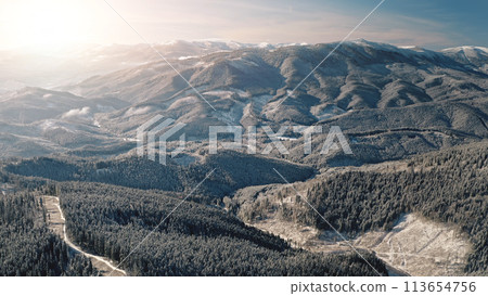 Sun over snow mountain ridges aerial. Nobody nature landscape at winter sunny day. Pine trees at mount hills, peak. Fir forest at sunlight. Carpathian, Bukovel, Ukraine, Europe. Travel, tourism Sun over snow mountain ridges aerial. Nobody nature landscape at winter sunny day. Pine trees at mount hills, peak. Fir forest at sunlight. Carpathian, Bukovel, Ukraine, Europe. Travel, tourism 113654756