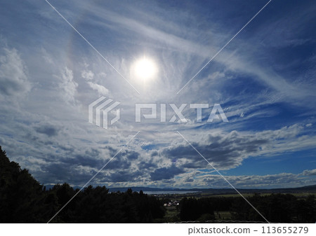 The thin clouds spreading over Lake Inawashiro and the shining white sun against the blue sky are an impressive and beautiful sight. The thin clouds spreading over Lake Inawashiro and the shining white sun against the blue sky are an impressive and beautiful sight. 113655279