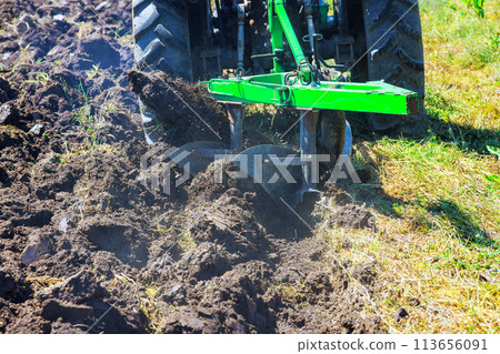 In spring, tractor plows are used to cultivate soil and prepare field for sowing grain 113656091