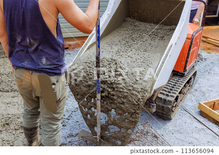 During construction of foundation, wet cement is poured into framework from concrete buggy using concrete buggy truck During construction of foundation, wet cement is poured into framework from concrete buggy using concrete buggy truck 113656094