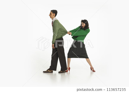 Emotionless young man walking away while woman pulling his with sweater. Emotional lifestyle situation of married couple Emotionless young man walking away while woman pulling his with sweater. Emotional lifestyle situation of married couple 113657235