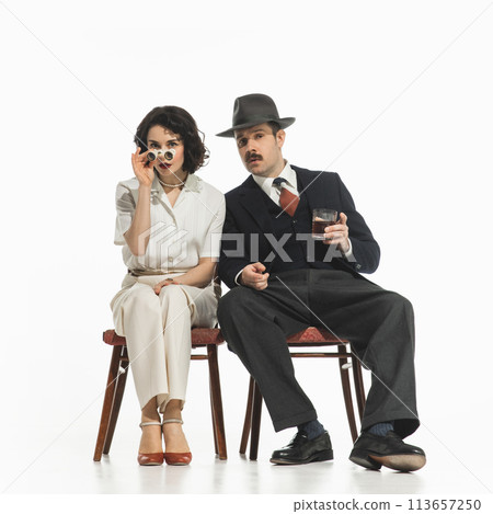 Elegant stylish couple, man and woman in classical suits with binoculars sitting and watching performance Elegant stylish couple, man and woman in classical suits with binoculars sitting and watching performance 113657250