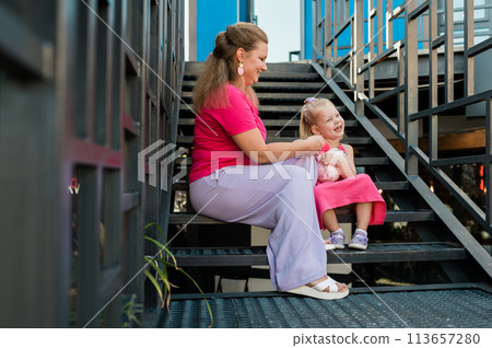Blonde little girl with cochlear implant playing with her mother outdoor. Hear impairment deaf and health concept. Diversity and inclusion. Copy space 113657280