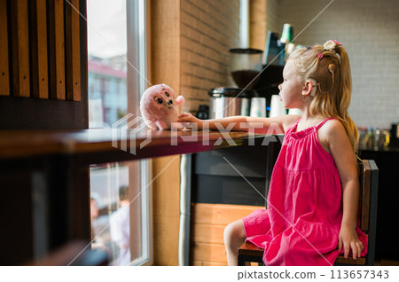 Funny child with cochlear implant in cafe. Hearing aid and medicine innovating technology concept. Diversity and inclusion. Copy space Funny child with cochlear implant in cafe. Hearing aid and medicine innovating technology concept. Diversity and inclusion. Copy space 113657343