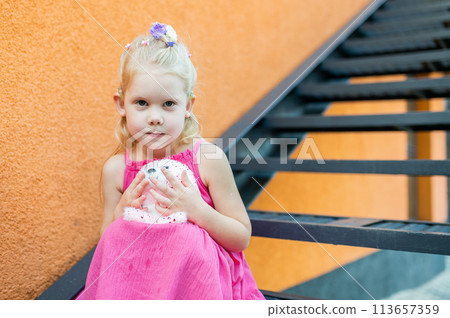 Child girl walks and have fun outdoor with cochlear implant on the head. Hearing aid and treatment concept. Copy space. Inclusion 113657359