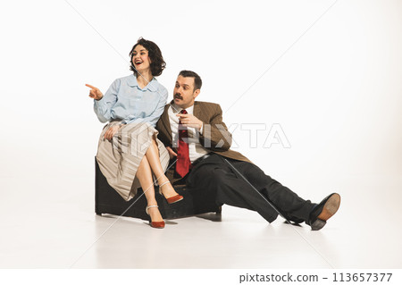 Elegant young woman and man in classical retro clothes sitting, looking away, pointing and taking, white background. Discussing, rumors, gossips Elegant young woman and man in classical retro clothes sitting, looking away, pointing and taking, white background. Discussing, rumors, gossips 113657377