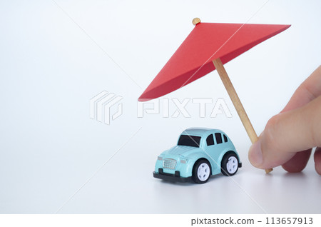 Toy car covered with toy umbrella representing car insurance concept Toy car covered with toy umbrella representing car insurance concept 113657913