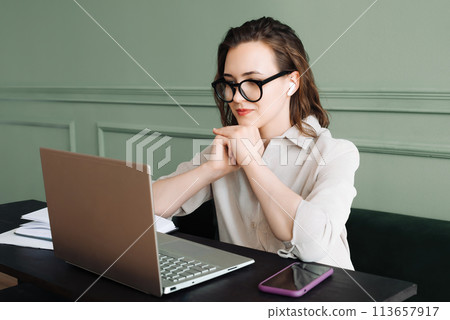 Connected and Smiling. Woman with Wireless Headphones Engages in Laptop Video Call with Joy. Digital 113657917