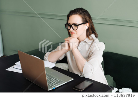Connected and Smiling. Woman with Wireless Headphones Engages in Laptop Video Call, Watching and 113657919