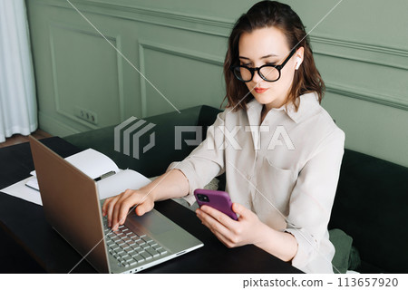 Productive Conversations. Woman Balancing Laptop and Smartphone in Video Call. Multitasking Joy Productive Conversations. Woman Balancing Laptop and Smartphone in Video Call. Multitasking Joy 113657920