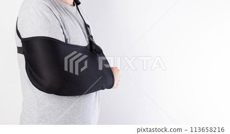 A man on a white background in a bandage to support his arm. Immobilization of the hand and forearm after injury. Rehabilitation after a broken bone. Orthopedics, copy space for text 113658216