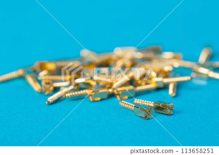 Lots of metal dental pins on a blue background. The concept of installing a tooth and a dental crown on pins in orthodontics, macro Lots of metal dental pins on a blue background. The concept of installing a tooth and a dental crown on pins in orthodontics, macro 113658251