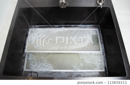 kitchen hood filters for sinks with a modern oxygen cleaner for grease and stains. Washing and cleaning the kitchen, close-up. Chemical reaction 113658311