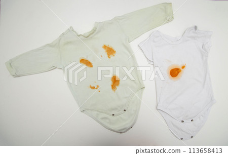 Orange stains on children's clothes from fruit puree. The concept of cleaning stains on clothes with an oxygen stain remover, close-up 113658413