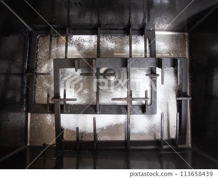 Dirty gas stove grates in the sink with a modern oxygen cleaner for kitchen cleaning. Cleaning the kitchen, removing grease stains, close-up 113658439