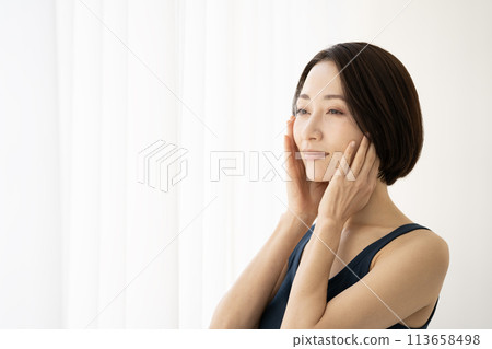 A woman doing skin care by the window A woman doing skin care by the window 113658498