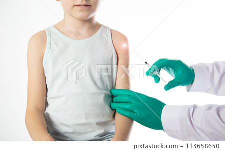 Doctor's hands in green medical gloves vaccinate a child girl in the shoulder against the flu, copy space for text. Revaccination Doctor's hands in green medical gloves vaccinate a child girl in the shoulder against the flu, copy space for text. Revaccination 113658650