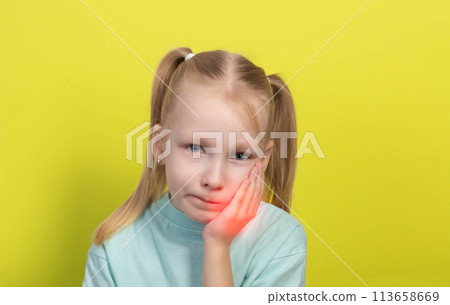A little girl aged seven years old holds her cheek with her hands on a yellow background. Concept of tooth pain in children, caries and pulpitis. Inflammation of the gums, dentistry. Salivary glands A little girl aged seven years old holds her cheek with her hands on a yellow background. Concept of tooth pain in children, caries and pulpitis. Inflammation of the gums, dentistry. Salivary glands 113658669