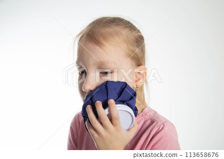 A seven-year-old girl applies a cold compress to a sore tooth. Relieving inflammation and pain in the tooth with cold, close-up. Local cryotherapy 113658676