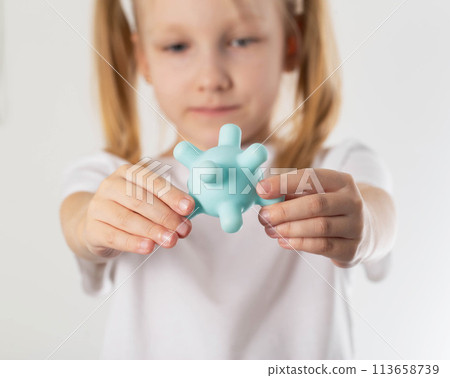 A blonde caucasian girl holds a model of a virus in her hands against the background of her face. Concept of scarlet fever and rubella infections in children, close-up A blonde caucasian girl holds a model of a virus in her hands against the background of her face. Concept of scarlet fever and rubella infections in children, close-up 113658739