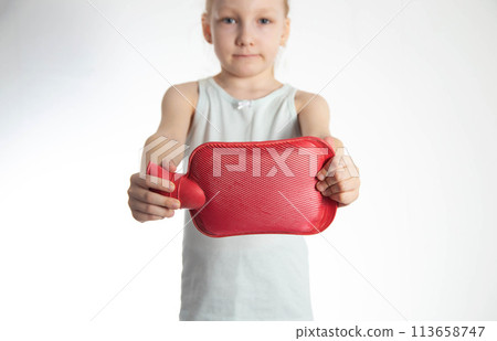 The girl holds a red heating pad with warm water in her hands at outstretched arms. Heat treatment concept. Improves digestion, treats the gallbladder with heat. 113658747