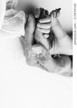 Close-up little hand of child and palm of mother and father. The newborn baby has a firm grip on the parent's finger after birth. A newborn holds on to mom's, dad's finger. Black and white photo. Close-up little hand of child and palm of mother and father. The newborn baby has a firm grip on the parent's finger after birth. A newborn holds on to mom's, dad's finger. Black and white photo. 113659100
