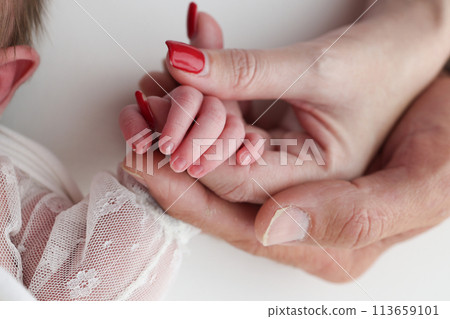Close-up little hand of child and palm of mother and father. The newborn baby has a firm grip on the parent's finger after birth. A newborn holds on to mom's, dad's finger. Close-up little hand of child and palm of mother and father. The newborn baby has a firm grip on the parent's finger after birth. A newborn holds on to mom's, dad's finger. 113659101