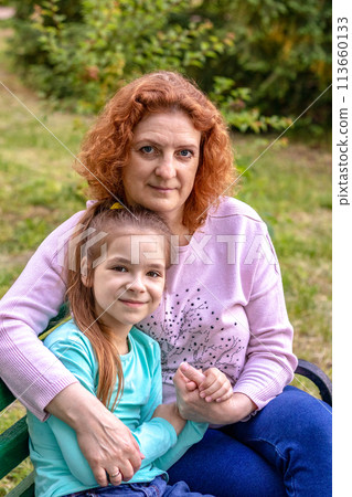 Portrait of a happy woman and daughter smiling and looking at the camera. 113660133