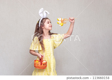 A girl with Easter bunny ears holds Easter props with Easter eggs. Easter is fun. A girl with Easter bunny ears holds Easter props with Easter eggs. Easter is fun. 113660158