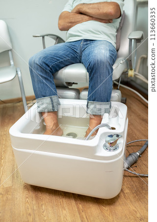 concept of male pedicure, cosmetologist makes classic pedicure for an elderly male client. 113660335