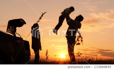 Silhouette of father tossing child in air. Family traveling by car having fun in nature laughing smiling enjoying life. Happy moments together. Loving dad with daughter and wife at weekend travel trip 113660645